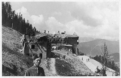 Photograph of Edgar Bowers standing behind the bombed remains of Hitler’s  house in Obersalzburg.