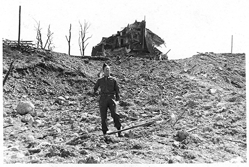 Photograph of Edgar Bowers standing in front of the bombed remains of Goering’s  house in Berchtesgaden.