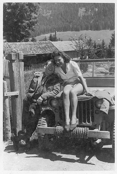 Photograph of Edgar Bowers and his friend Florence Tannenberger, seated on an Army jeep, in Gruenbueschel (June, 1945).  On the reverse: "Send this home to your mother to show her the horrors and hardships of war."